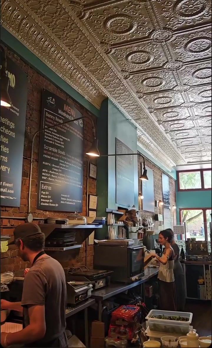 Staff at work behind the counter under the pressed-tin ceiling, chalkboard menus on the brick wall